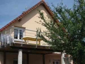 żółty dom z balkonem i drzewem w obiekcie 3A RUE JEAN BAPTISTE WENDLING w mieście Ribeauvillé
