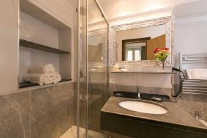ein Bad mit einem Waschbecken und einer Dusche mit einem Spiegel in der Unterkunft DK Suites in Rom