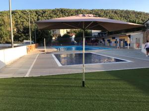 an umbrella sitting in the grass next to a pool at Castell D´Orpí in Orpí