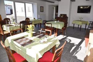 ein Restaurant mit Tischen und Stühlen mit grünem Tischtuch in der Unterkunft Pension LPG-Hof in Großpösna