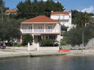 a house sitting on the side of a body of water at Apartments Ivona in Lumbarda