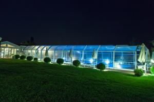 un grande edificio di vetro di notte con un prato di Agriturismo Lama Di Valle Rosa a Ferrara