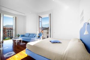 a white bedroom with a bed and a blue couch at La Casa dell'Orologio - MAIN SQUARE in Sorrento