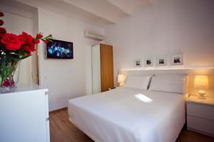 een slaapkamer met een wit bed en een vaas met rode rozen bij Ramblas Apartments in Barcelona