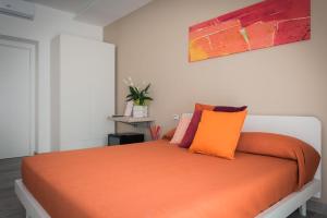 ein Schlafzimmer mit einem Bett mit orangefarbener Bettwäsche und Kissen in der Unterkunft L'Agrumeto in Procida