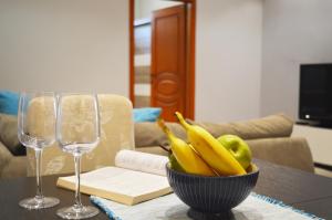 un bol de fruta en una mesa con dos copas de vino en Antigona Apartments, en Skopje