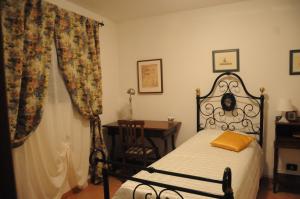 a bedroom with a bed and a desk and curtains at Il Molino Di Serravalle in Bibbiena