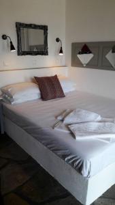 a large white bed in a bedroom with a mirror at Aperanto Galazio in Skopelos Town