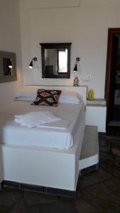 a large white bed in a room with a window at Aperanto Galazio in Skopelos Town