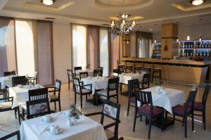 un restaurante con mesas y sillas blancas y un bar en Filokalia Hotel, en Ioannina