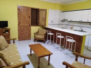 
a kitchen with a table, chairs and a refrigerator at Apartamentos La Banda in Playa de Santiago
