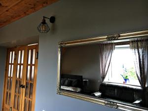 a mirror in a room with a couch and a window at Vila su sauna ir kubilu gamtos apsuptyje in Kalviškiai