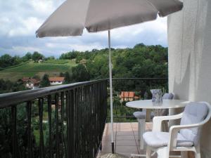 einen Balkon mit einem Tisch und einem Sonnenschirm in der Unterkunft Apartments Country House Stipica in Tuheljske Toplice