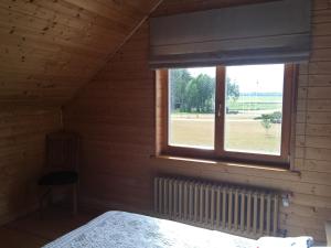 een slaapkamer met een raam met uitzicht op een veld bij Amoliņi in Mērsrags