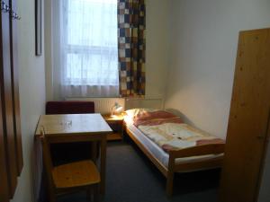 プラハにあるホテル ハサのベッド、テーブル、窓が備わる小さな客室です。