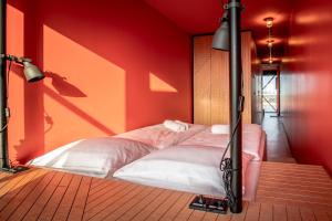 Bett in einem Zimmer mit roter Wand in der Unterkunft DOCK INN Hostel Warnemünde in Warnemünde