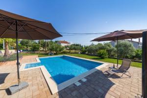 a swimming pool with two umbrellas and two chairs at Apartment Alex in Zadar