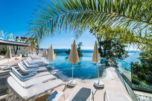 a pool with white lounge chairs and umbrellas at Grand Hotel Adriatic in Opatija