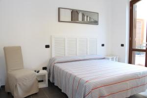 1 dormitorio blanco con 1 cama y 1 silla en L'incanto del mare, en Acciaroli