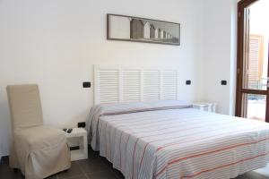 a white bedroom with a bed and a chair at L'incanto del mare in Acciaroli