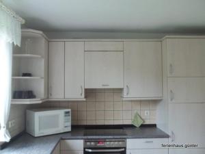 a kitchen with white cabinets and a white microwave at Ferienhaus Günter in Forchtenberg +14 photos