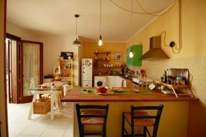 a kitchen with a counter with chairs and a table at Giardino Dei Suoni B&B in Melendugno