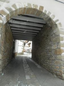 un callejón con una pared de piedra y un arco en Hostal El Portalico, en Linares de Mora