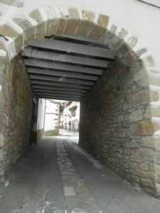 an alley with a stone wall and an archway at Hostal El Portalico in Linares de Mora