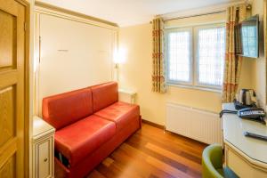 a living room with a red leather couch at Linton Hotel Luton in Luton