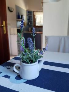 un vase blanc avec des fleurs violettes sur une table dans l'établissement Maslina Apartment, à Jadrtovac