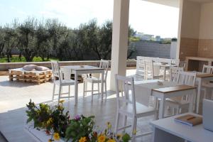 a patio with white tables and white chairs and flowers at Piccolo Ulivo B&B Salento in Vernole