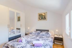 a white bedroom with a bed and two mirrors at Apartment Rusula in Milna