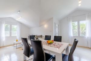 Un comedor con una mesa y sillas blancas. en Apartment Rusula, en Milna