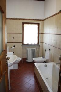 een badkamer met 2 toiletten, een bad en een wastafel bij L'Helleboro in Viggiù
