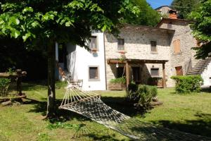 a house with a hammock in front of a building at Il Molino Di Serravalle in Bibbiena +24 photos
