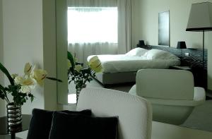 um quarto com uma cama e duas cadeiras e flores em G Hotel Ancona em Osimo