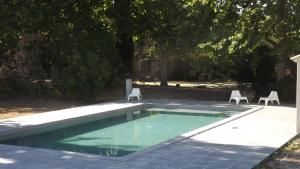 ein Pool mit zwei Gartenstühlen daneben in der Unterkunft La Bastide in Cavaillon