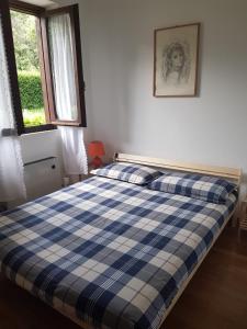 - un lit bleu et blanc dans une chambre avec fenêtre dans l'établissement Home Cremeno Valsassina, à Cremeno