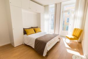 a bedroom with a bed with yellow pillows and a chair at Downtown Porto Mouzinho Studio Apts in Porto