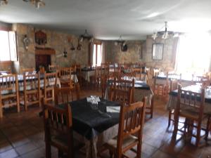 un comedor con mesas y sillas de madera y una habitación con mesas y sillas en Hostal El Portalico, en Linares de Mora