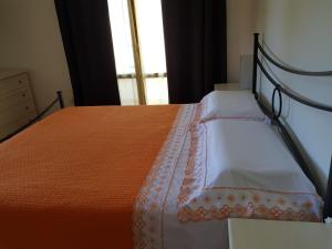 - une chambre avec un lit doté d'une couverture orange et d'une fenêtre dans l'établissement Alberese, à Alberese