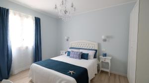 马卡里La Via dell'Acqua的一间白色的卧室，配有一张蓝白色的床和一盏枝形吊灯