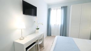 马卡里La Via dell'Acqua的白色卧室配有书桌和墙上的电视