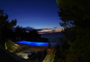 a swimming pool with a view of the ocean at night at Holiday house Karla in Vela Luka