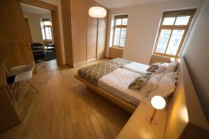 a bedroom with a bed and a desk and two windows at President Apartment in Sarajevo