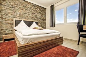 a bedroom with a bed and a brick wall at Hotel Maxis in Karlsbad