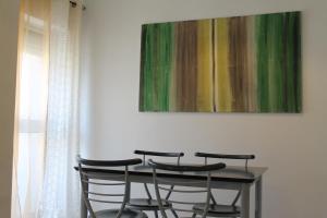 stół z 4 krzesłami i obraz na ścianie w obiekcie Charming baixa w mieście Lavradio