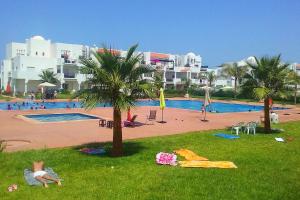ein Pool mit einer Palme im Gras in der Unterkunft Chez Younès Appartement Marina Saidia Ap8 in Saidia 