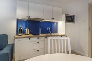una pequeña cocina con armarios blancos y fregadero en Apartamenty Draga, en Jastarnia