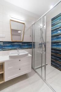 La salle de bains est pourvue d'un lavabo et d'une douche. dans l'établissement Apartamenty Draga, à Jastarnia